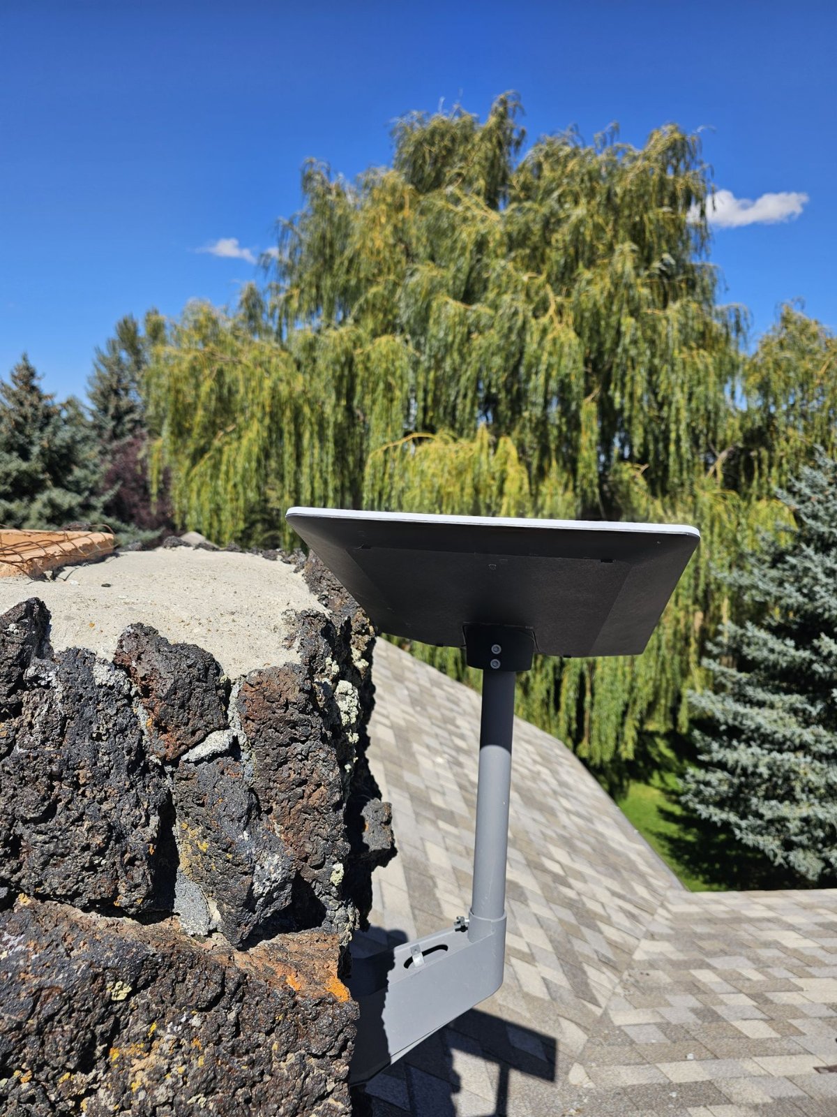 Starlink dish on a pole mount fixed to a lava-rock chimney